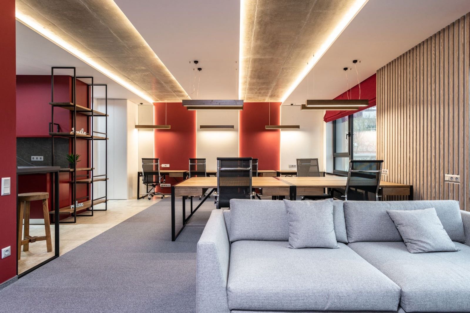 Oficina moderna y luminosa con zona de trabajo y sofá, cuidada al detalle